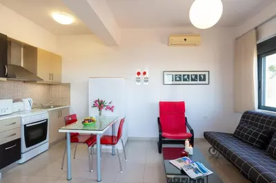 a kitchen and living room with a table and red chairs at Caravella Luxury Apartments in Palaiochóra