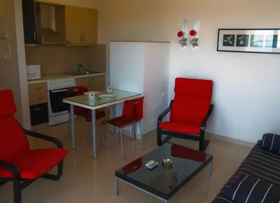 a living room with red chairs and a table at Caravella Luxury Apartments in Palaiochóra