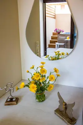 a vase of yellow flowers on a table in front of a mirror at Aretousa Suites in Chania Town