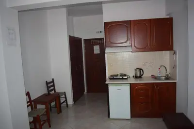 a kitchen with wooden cabinets and a table and chairs at Zorbas Studios in Agia Roumeli