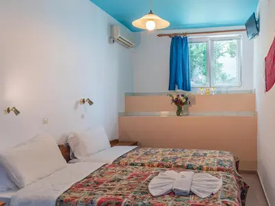 a bedroom with two beds and a window and a bed at Haris Studios in Palaiochóra
