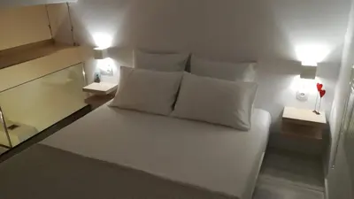a bedroom with a white bed with pillows and lamps at Sixteen All Seasons House in Chania Town