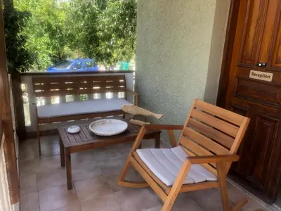 a porch with a chair and a table and a bench at Nicolas Beach in Palaiochóra