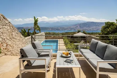 a patio with two chairs and a table and a pool at Villa Anemi in Stérnai