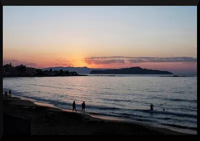 a group of people standing on the beach at sunset at Iolkos Hotel Apartments in Kato Daratso