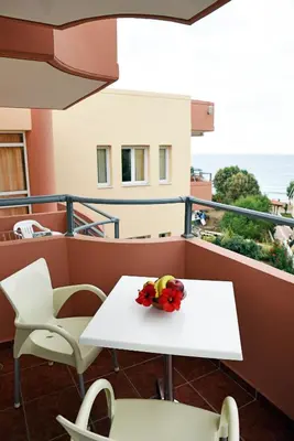 a table and chairs on a balcony with the ocean at Iolkos Hotel Apartments in Kato Daratso