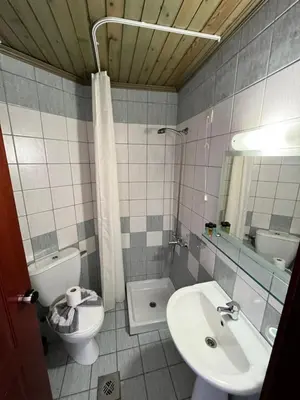 a bathroom with a sink and a toilet and a mirror at Iolkos Hotel Apartments in Kato Daratso