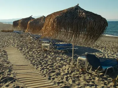 a row of chairs and umbrellas on a beach at Hippokratis Apartments in Gerani Chanion