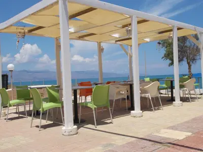 a patio with a table and chairs and the ocean at Hippokratis Apartments in Gerani Chanion