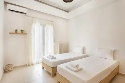 two beds in a white room with a window at Mirsini's Apartment in Chania center in Chania Town