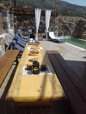 a wooden table with food on it next to a pool at Villa Aeolus with private overflow, endless, heated pool in Prinés