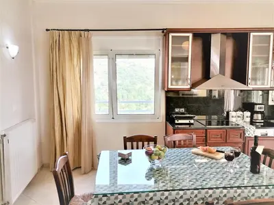 a kitchen with a dining room table and a window at Villa Aeolus with private overflow, endless, heated pool in Prinés