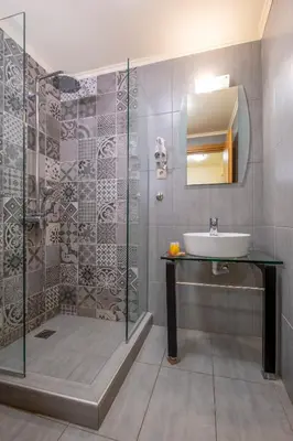 a bathroom with a sink and a shower with a mirror at Areti Suites in Kathiana