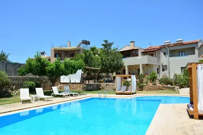 a swimming pool with two chairs and a house at Elianthos Villas in Vamos