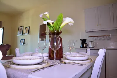 a table with plates and glasses and a vase with flowers at Elianthos Villas in Vamos