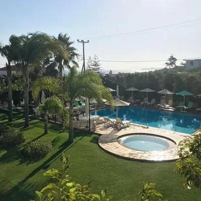 a swimming pool in a yard with palm trees at Kalithea Apartments - Heated Pool in Kalyves