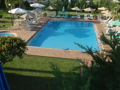 a large swimming pool with chairs and umbrellas at Kalithea Apartments - Heated Pool in Kalyves