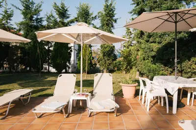 a patio with a table and chairs and an umbrella at Kalithea Apartments - Heated Pool in Kalyves