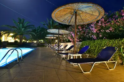a row of chairs with umbrellas next to a pool at Flisvos Rooms in Palaiochóra
