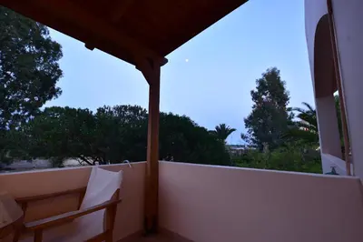 a balcony with a table and a chair on a wall at Flisvos Rooms in Palaiochóra