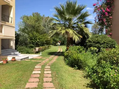 a person standing in a yard with a palm tree at Marita's Apartments in Agia Marina Nea Kydonias