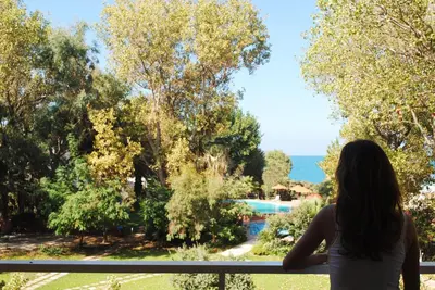 a woman standing on a balcony looking out at the ocean at Marita's Apartments in Agia Marina Nea Kydonias