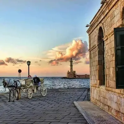 a man in a horse drawn carriage in front of a lighthouse at Ontas Villa Loutraki Platanias in Gerani Chanion