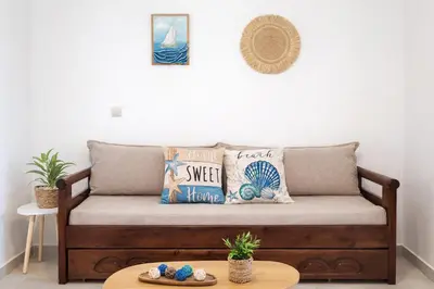a couch in a living room with pillows and a table at Konstantina's cottage Ideal BaseforBalos & Elafonisi in Kissamos