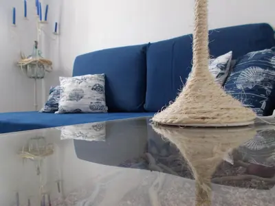 a living room with a glass table and a blue couch at Dimitra's Sea-Crafts Boutique Studios in Kalyves