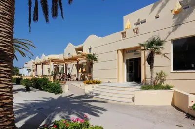 a building with palm trees in front of it at Lambrinos Suites in Plataniás