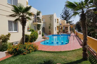 a swimming pool in the yard of a house with palm trees at Lambrinos Suites in Plataniás