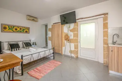 a living room with a bed and a tv on the wall at Grandma's Nest in Kissamos