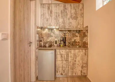 a small kitchen with wooden cabinets and a refrigerator at Vitis Vinifera Tranditional Studio Apartment in Kissamos