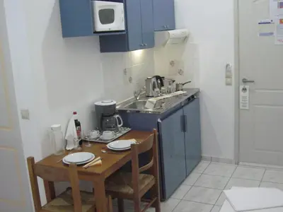 a small kitchen with blue cabinets and a table with chairs at Despina Studios in Agia Marina Nea Kydonias