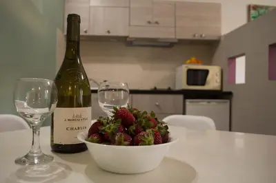 a table with a bowl of strawberries and a bottle of wine at Nireas Hotel in Kato Daratso