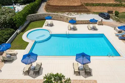 an overhead view of a swimming pool with blue umbrellas at IRINI STALOS Apartments in Stalos