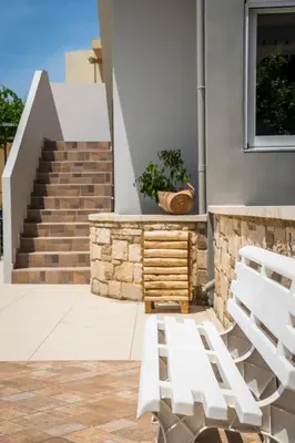 a pair of white chairs on a patio with stairs at IRINI STALOS Apartments in Stalos