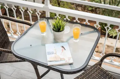 a glass table on a balcony with two glasses of orange juice at IRINI STALOS Apartments in Stalos