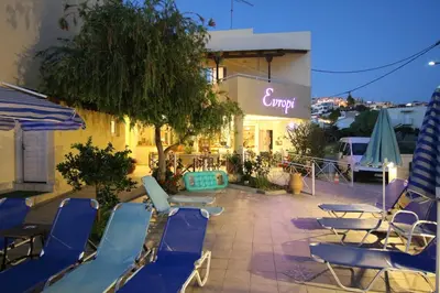 a group of chairs and umbrellas in front of a building at Evropi Hotel in Plataniás