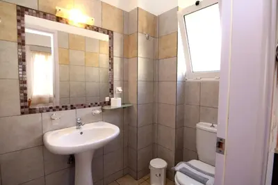 a bathroom with a sink and a toilet and a mirror at Evropi Hotel in Plataniás