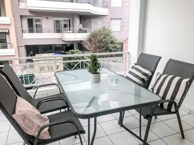 a glass table and chairs on a balcony at Sofia City Beach 3 Apts Nea Chora Chania steps from the beach in Chania Town