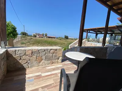 a patio with a table and a stone wall at Blue Sky in Frangokastello