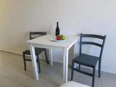 a white table with a plate of fruit and a bottle of wine at Amaryllis in Plataniás