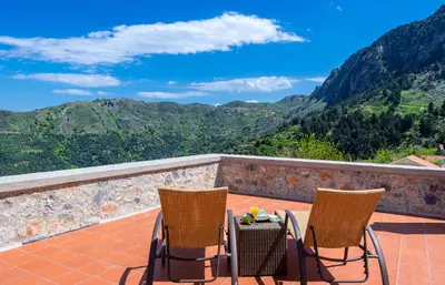 two chairs and a table on a balcony with mountains at Apirathes Residence in Zoúrva