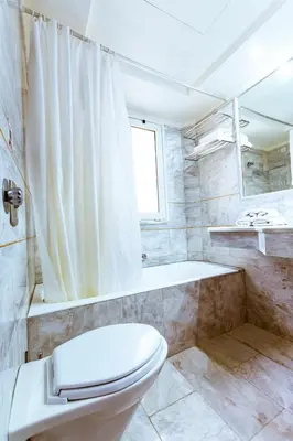 a bathroom with a toilet and a shower and a tub at Anais Collection Hotels & Suites in Kato Daratso