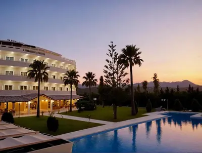 a hotel with a swimming pool and palm trees at Regina Hotel in Kissamos