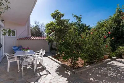 a patio with a table and chairs and a tree at Niki's Apartment in Palaiochóra