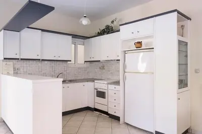 a white kitchen with white cabinets and a refrigerator at Niki's Apartment in Palaiochóra