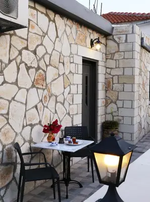 a table and chairs on a patio with a stone wall at Archontiko Haris in Kolymvari