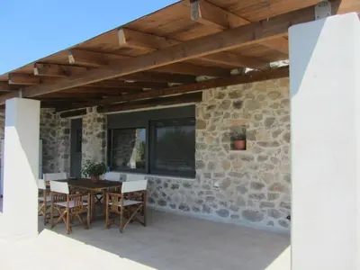 a patio with a table and chairs and a stone wall at VILLA ASTERAKI private pool, magic sunsets, near Elafonisi in Ãyios FÃ³tios